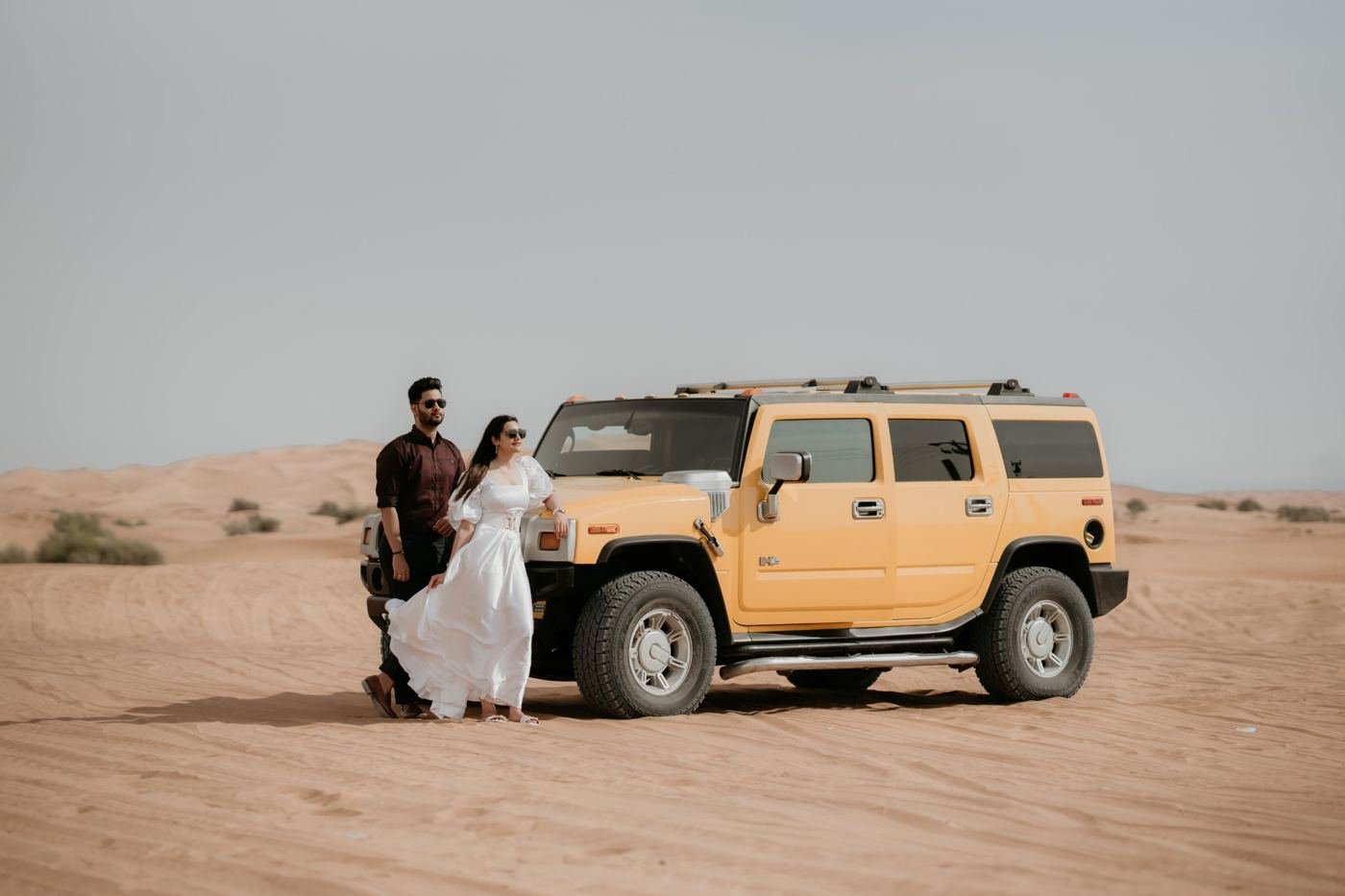 Couple beside a yellow 4x4 in the Dubai desert